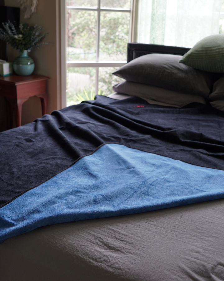 Black waterproof blanket on a bed showing blue underside