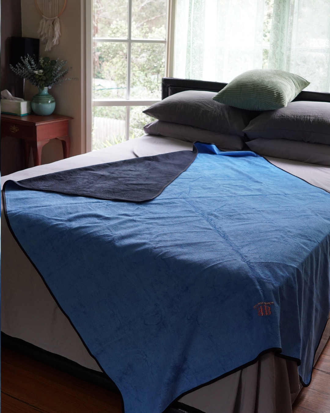 Blue waterproof blanket draped over a bed showing black reverse