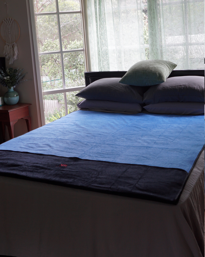 Blue side of the waterproof blanket laid across a bed