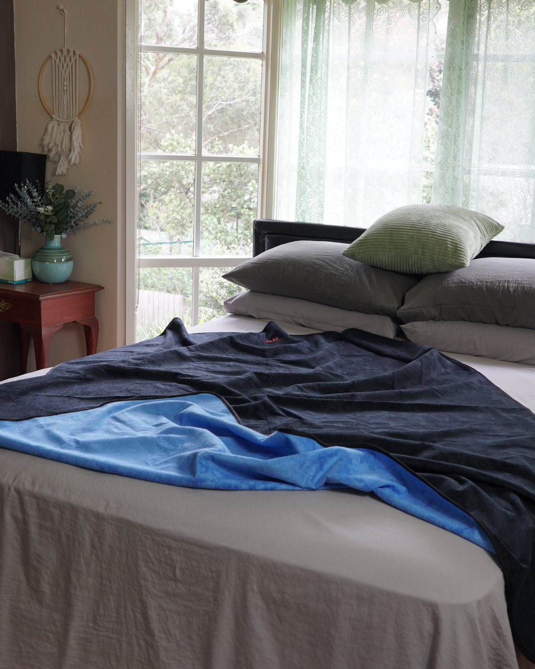 Black and blue reversible waterproof blanket loosely draped across a bed
