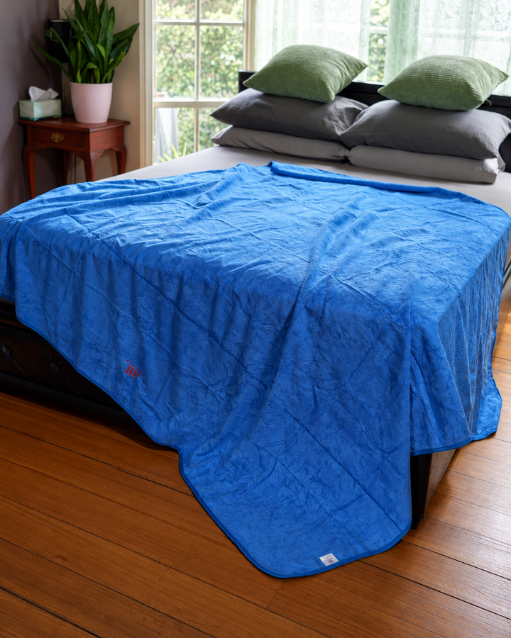 Capri Blue Luxury 200 × 200 cm bamboo and cotton waterproof blanket draped over a bed