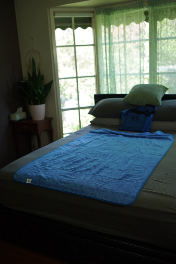 Capri Blue Regular 150 × 100 cm waterproof blanket laid on a bed showing its compact coverage