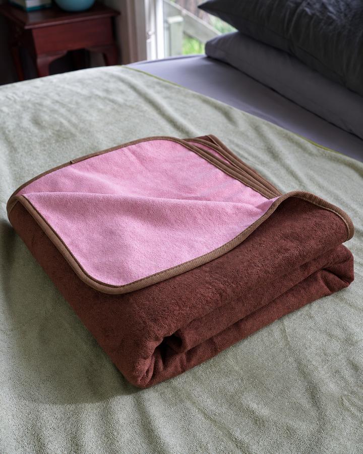 Folded Coffee and Pink waterproof blanket showing its fabric texture and bound edges