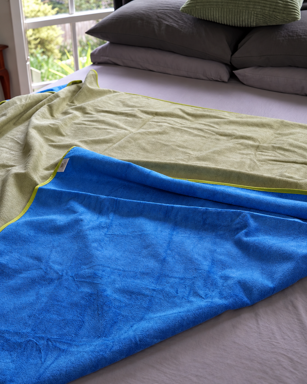 Soft folds of Capri Blue and Matcha Mist reversible blanket fabric