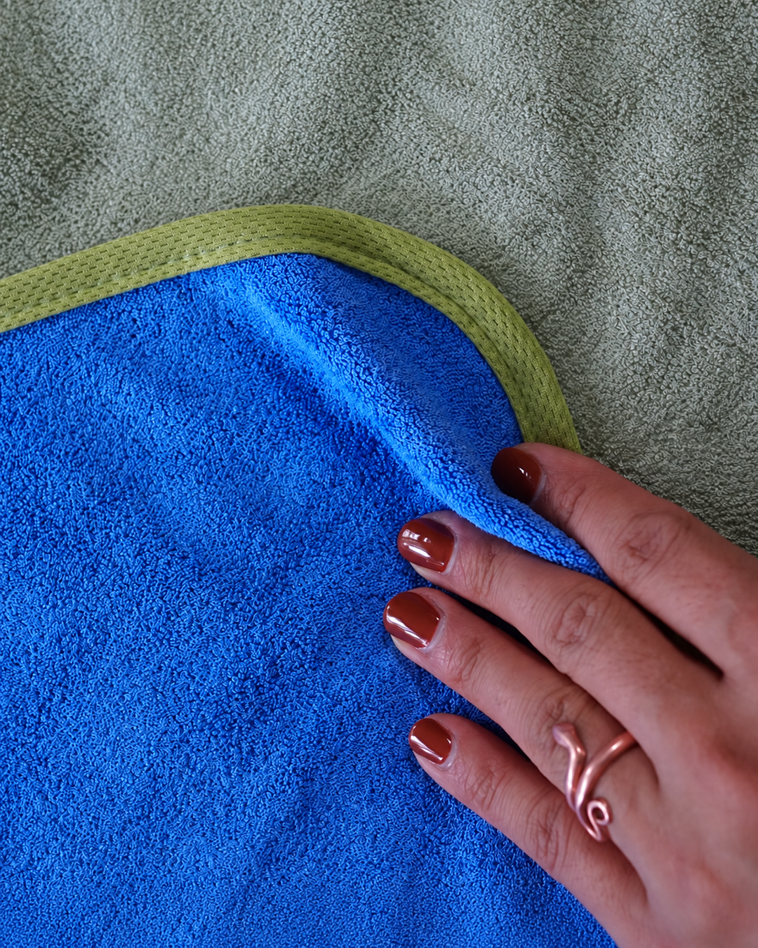 Hand touching Capri Blue bamboo and cotton fabric beside the Matcha Mist edging