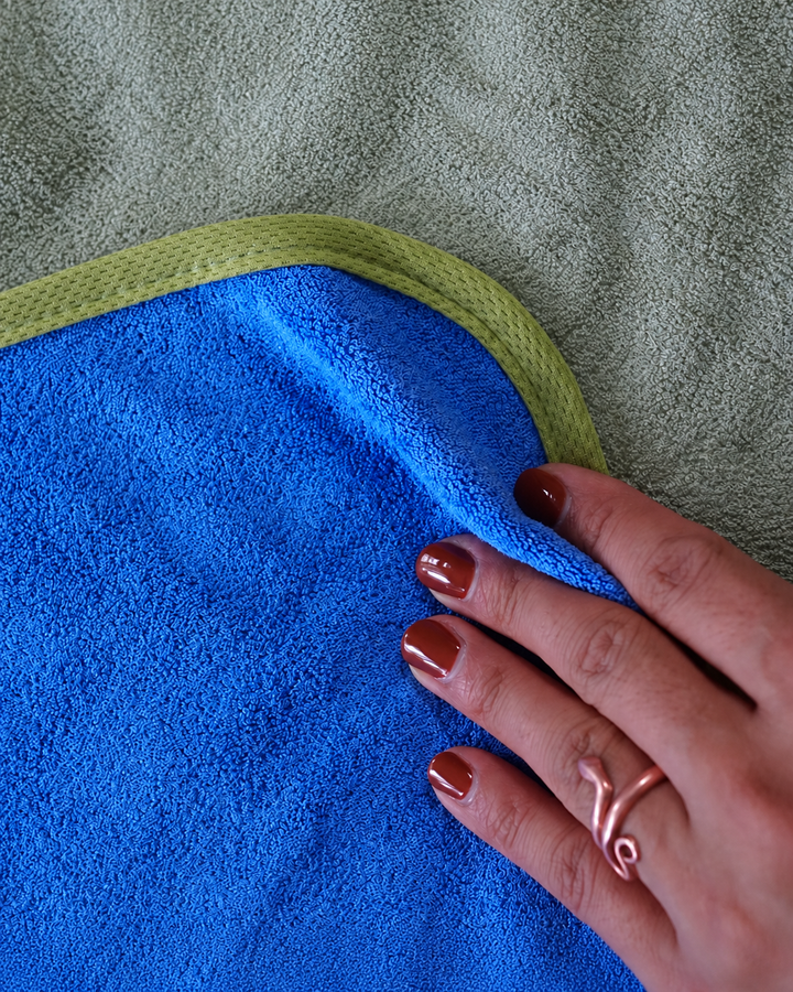 Hand touching Capri Blue bamboo and cotton fabric beside the Matcha Mist edging