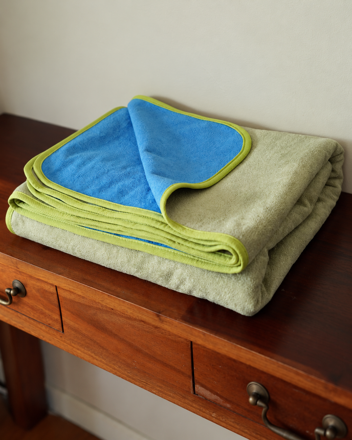 Angled view of the folded Matcha Mist and Capri Blue waterproof blanket
