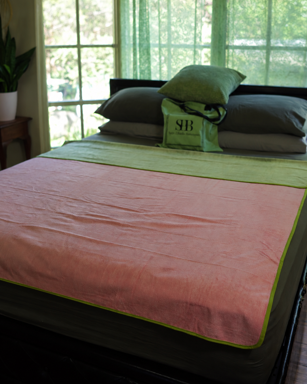 Pink waterproof blanket laid flat on a bed with Matcha Mist reverse turned back