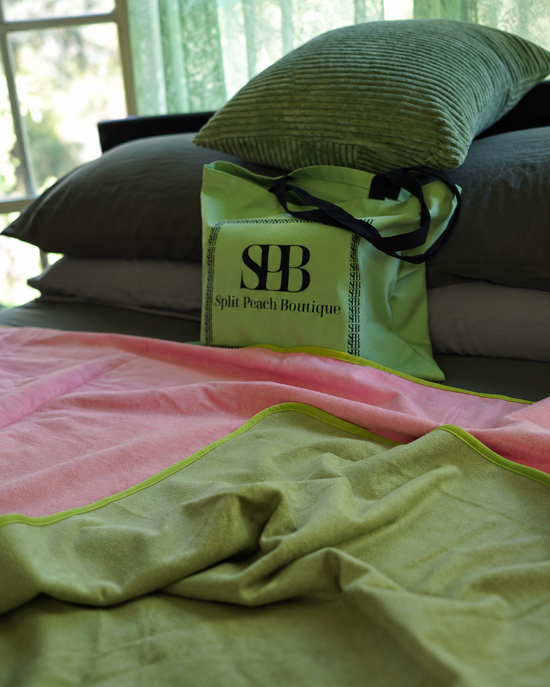Soft folds of Matcha Mist and Pink bamboo and cotton fabric beside Split Peach branded bag